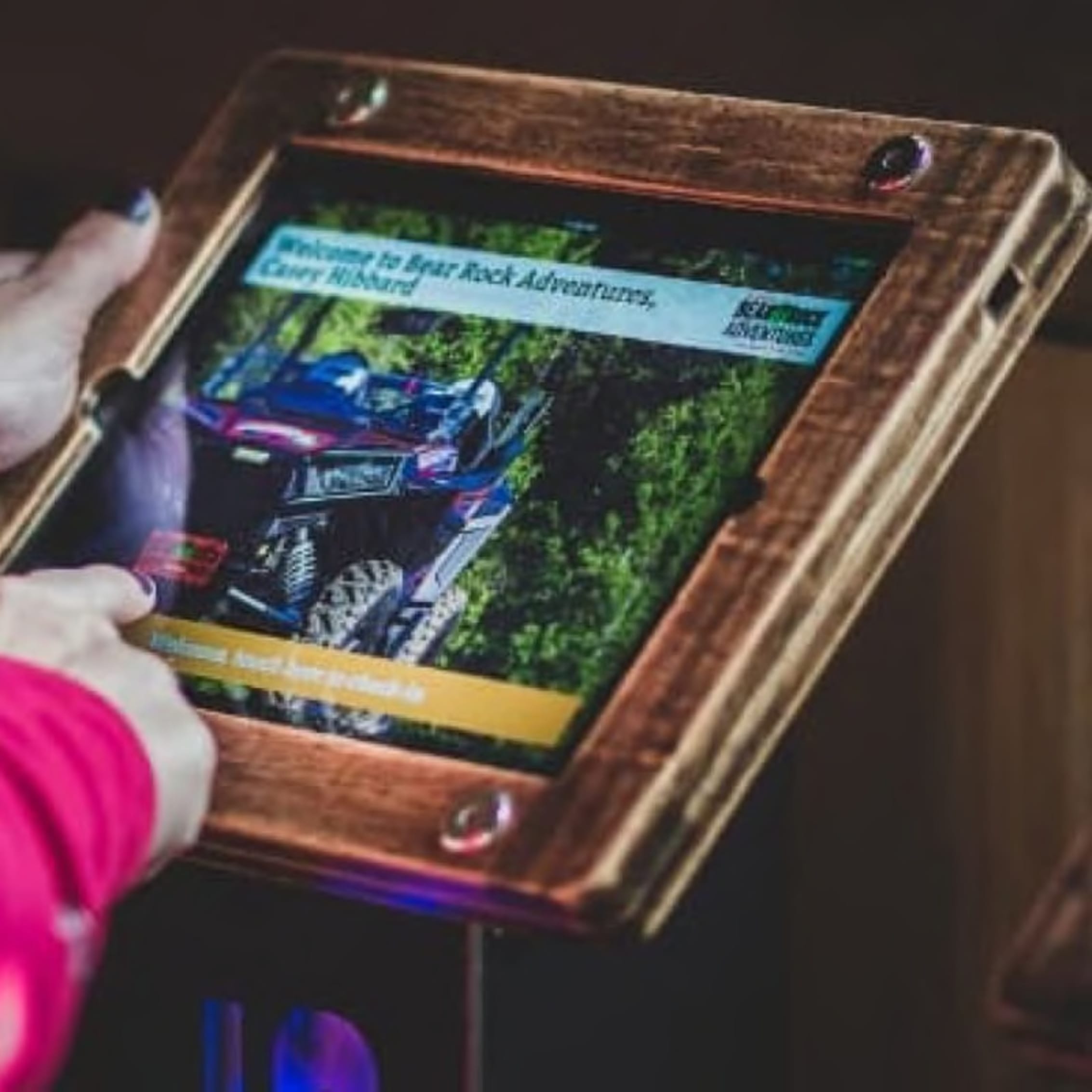 Person browsing an outdoor adventure touchscreen kiosk with Polaris ATV imagery.