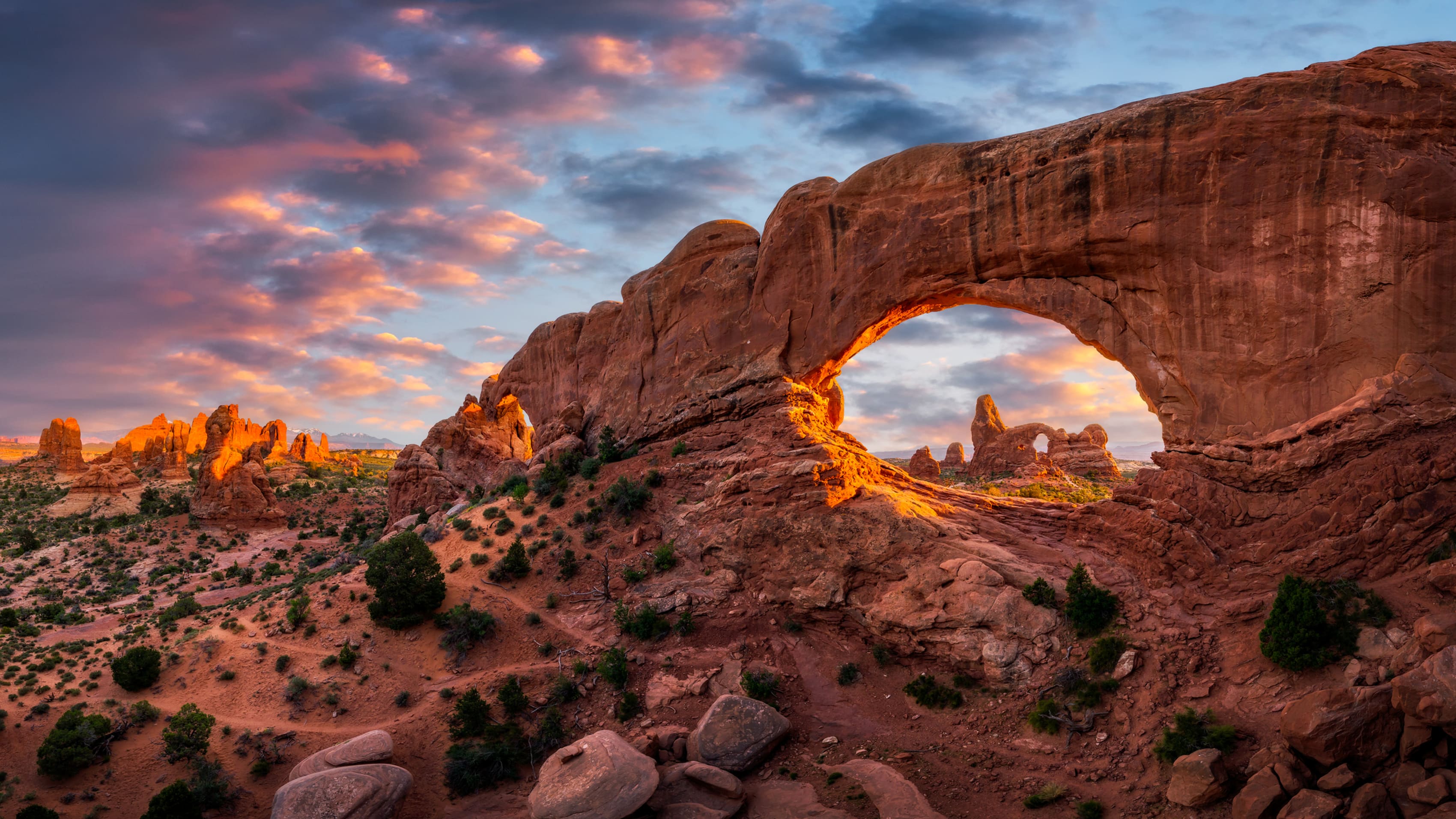 Sunset view of a natural archway in Gateway National Park with warm light on rocks