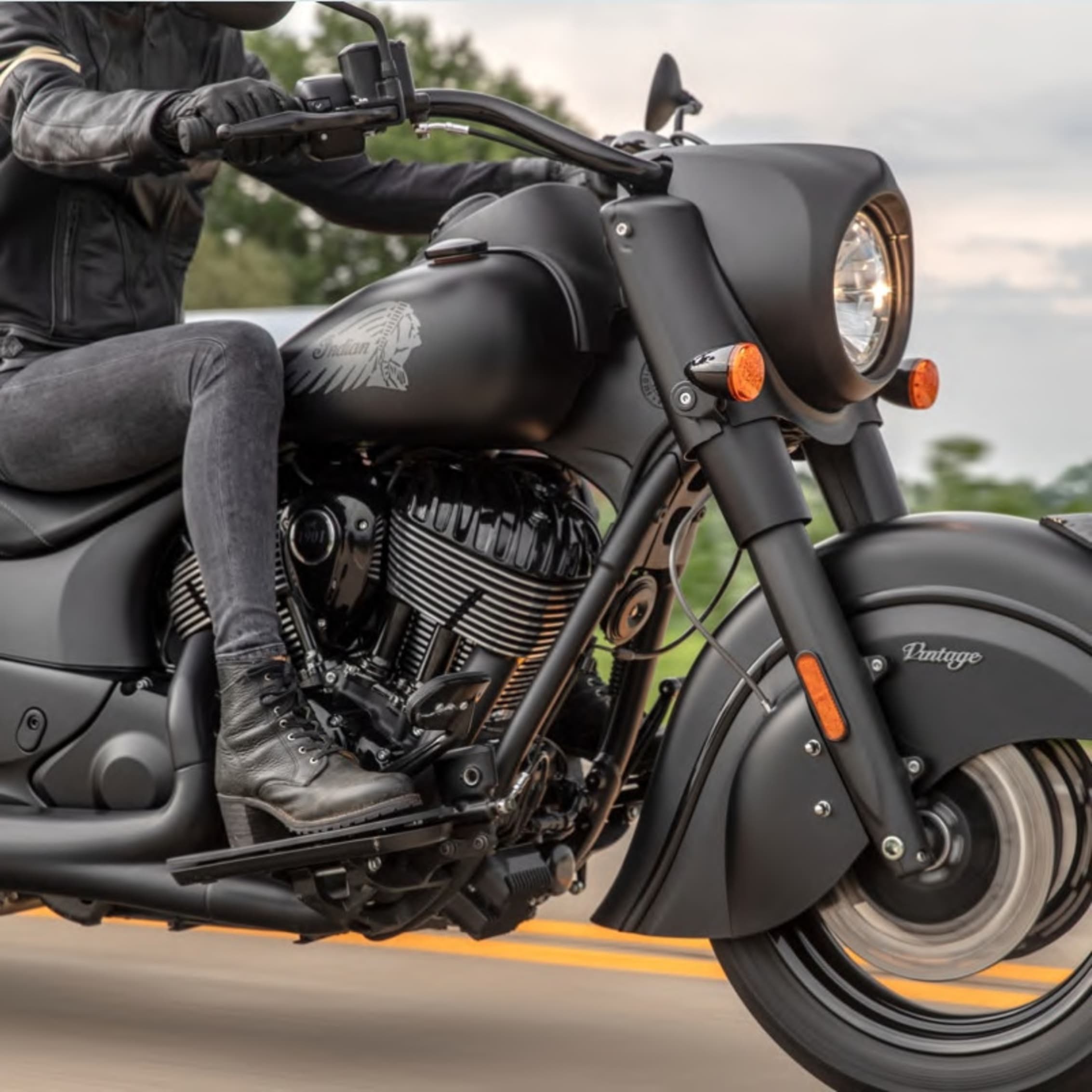 Rider on a matte black Indian Vintage motorcycle, showcasing the iconic styling and road presence on a serene ride.