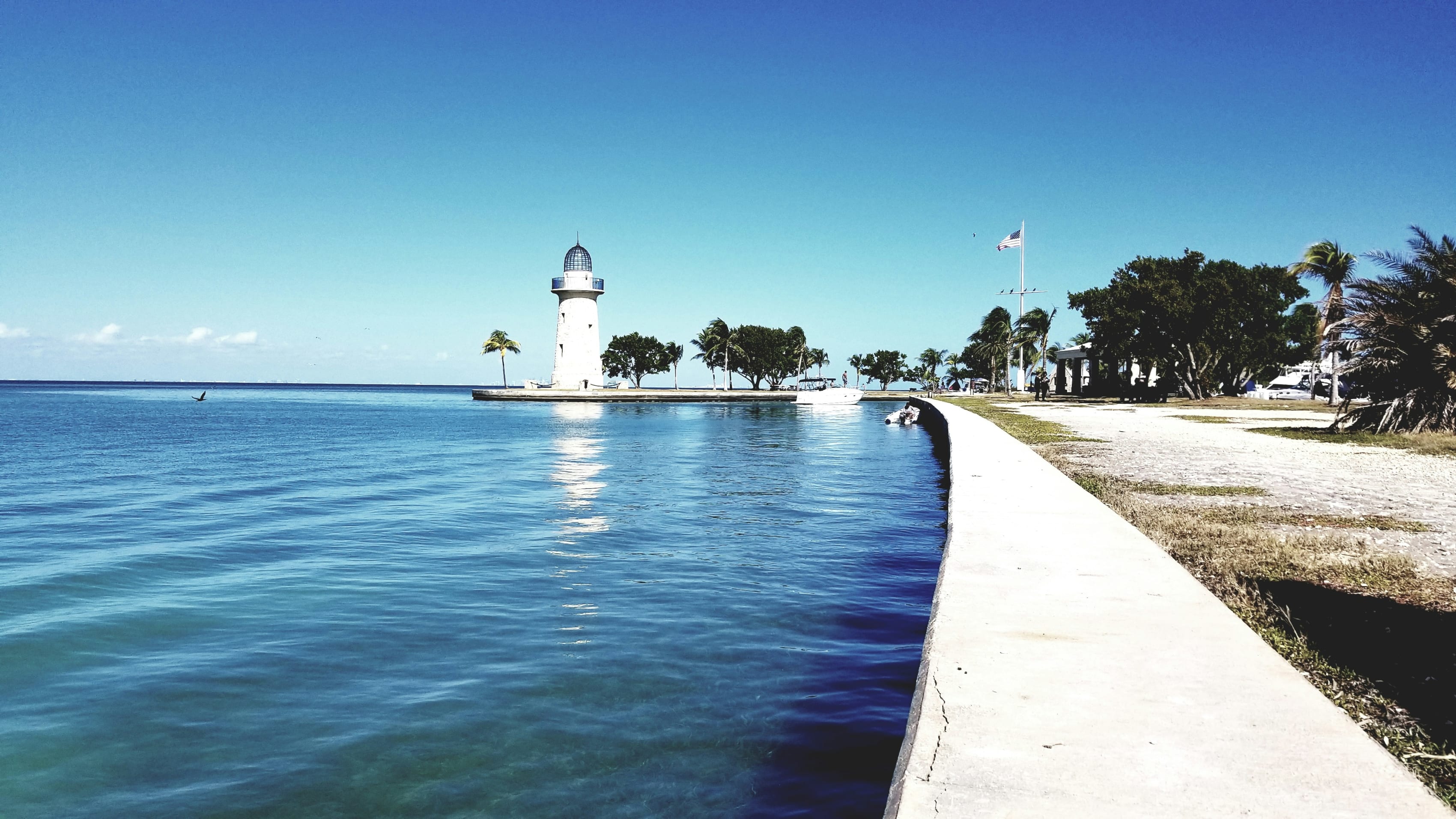Biscayne National Park coastal view with a lighthouse, tranquil blue waters and a clear sky, promoting serene adventures.