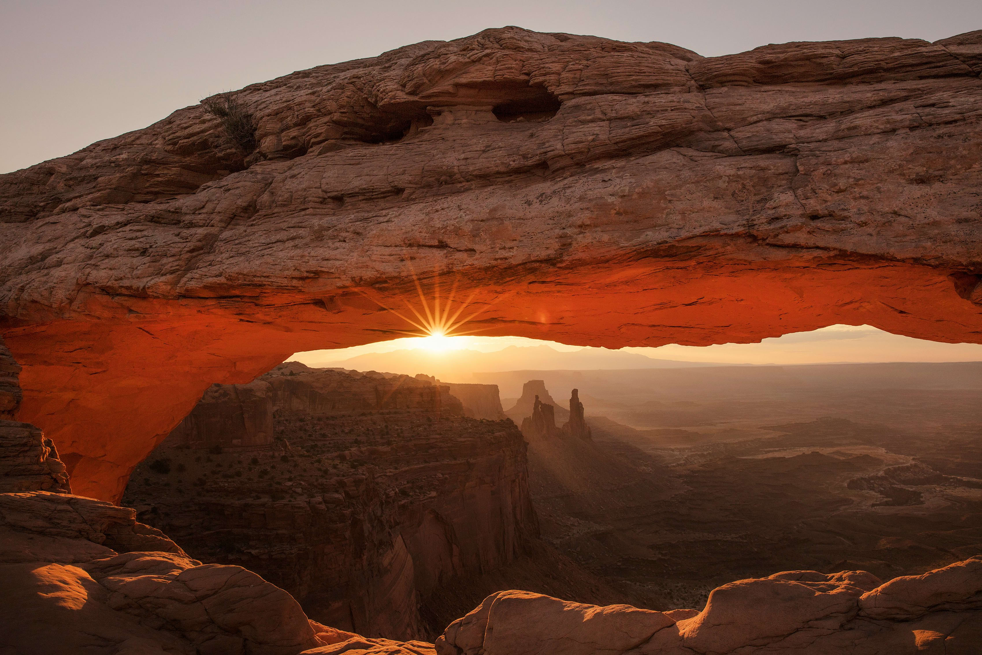 Sunrise at Canyonlands National Park, sunlight peeking through the Mesa Arch with stunning canyon views.