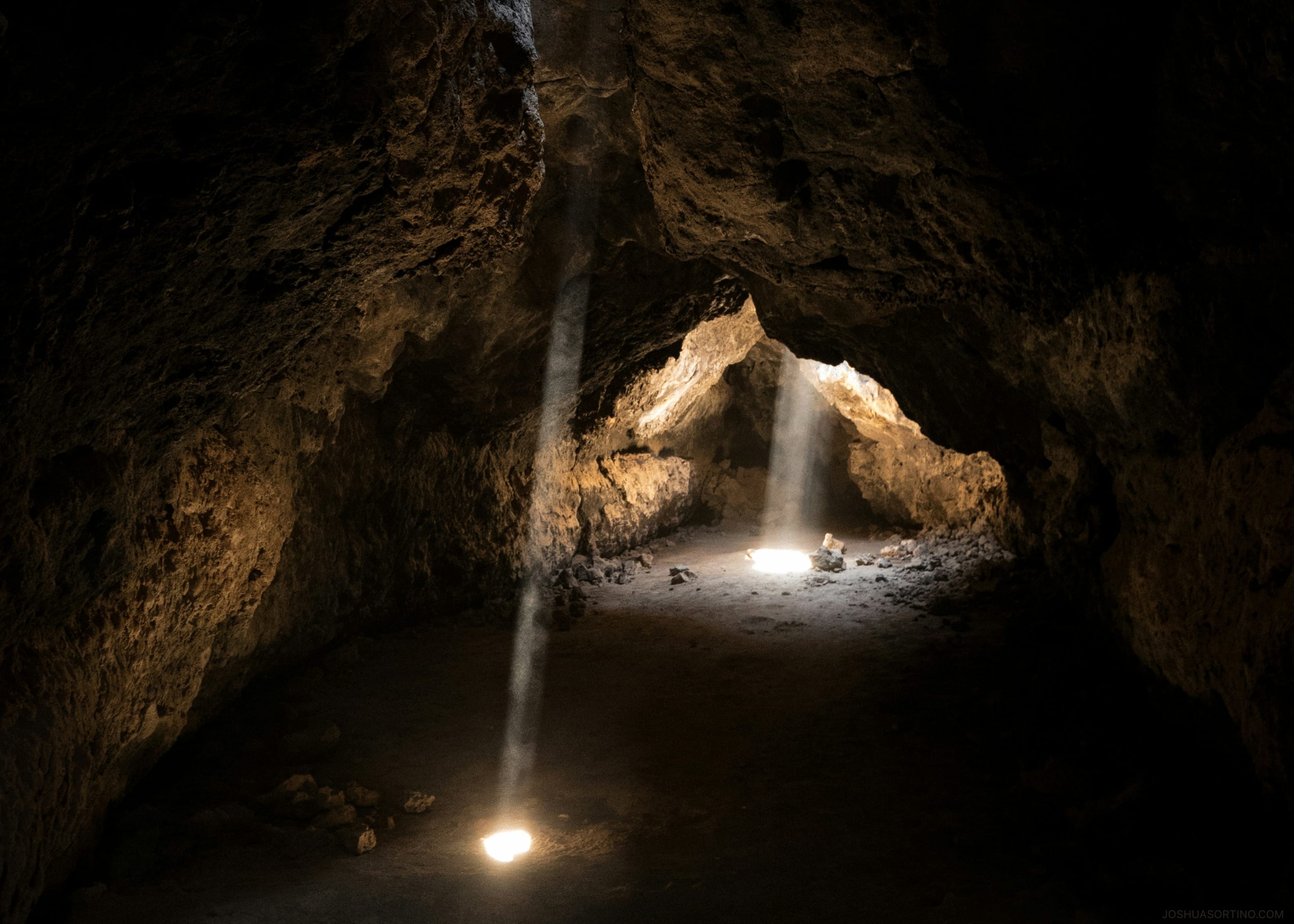 Shafts of sunlight breaking through the entrance of Mammoth Cave at a national park
