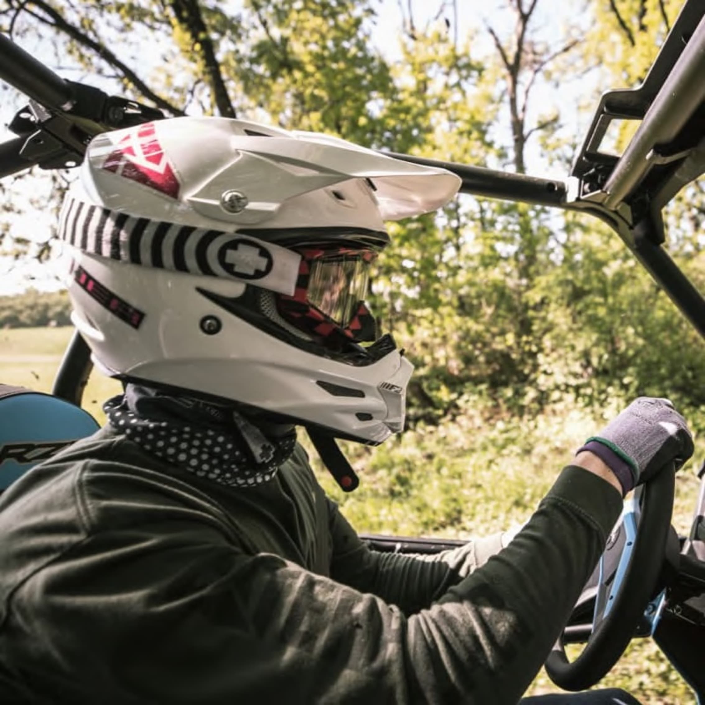 Close-up of a driver in a helmet and safety gear inside an off-road vehicle.