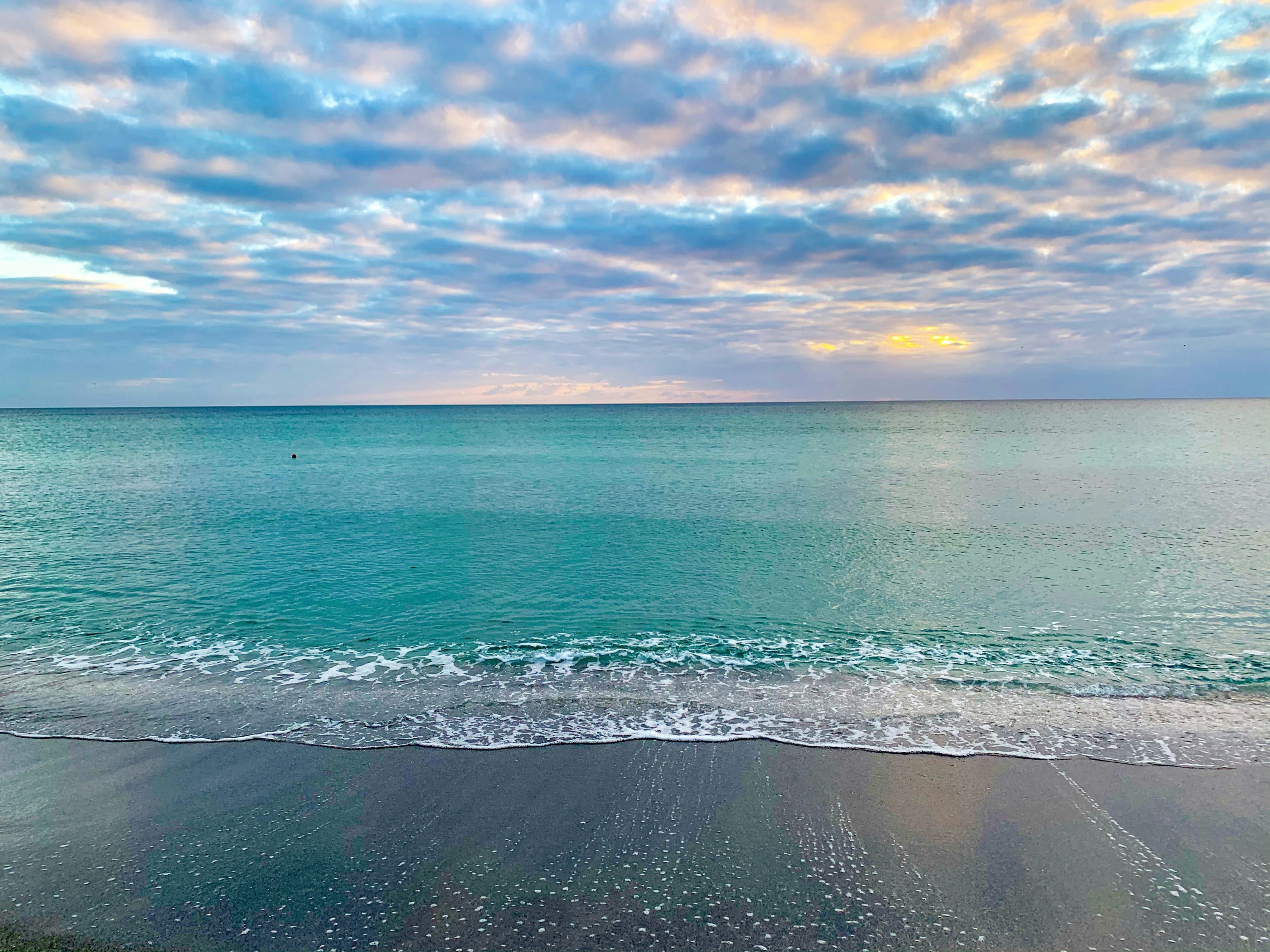 Serene Florida beach with gentle waves under a partly cloudy sky at sunrise or sunset