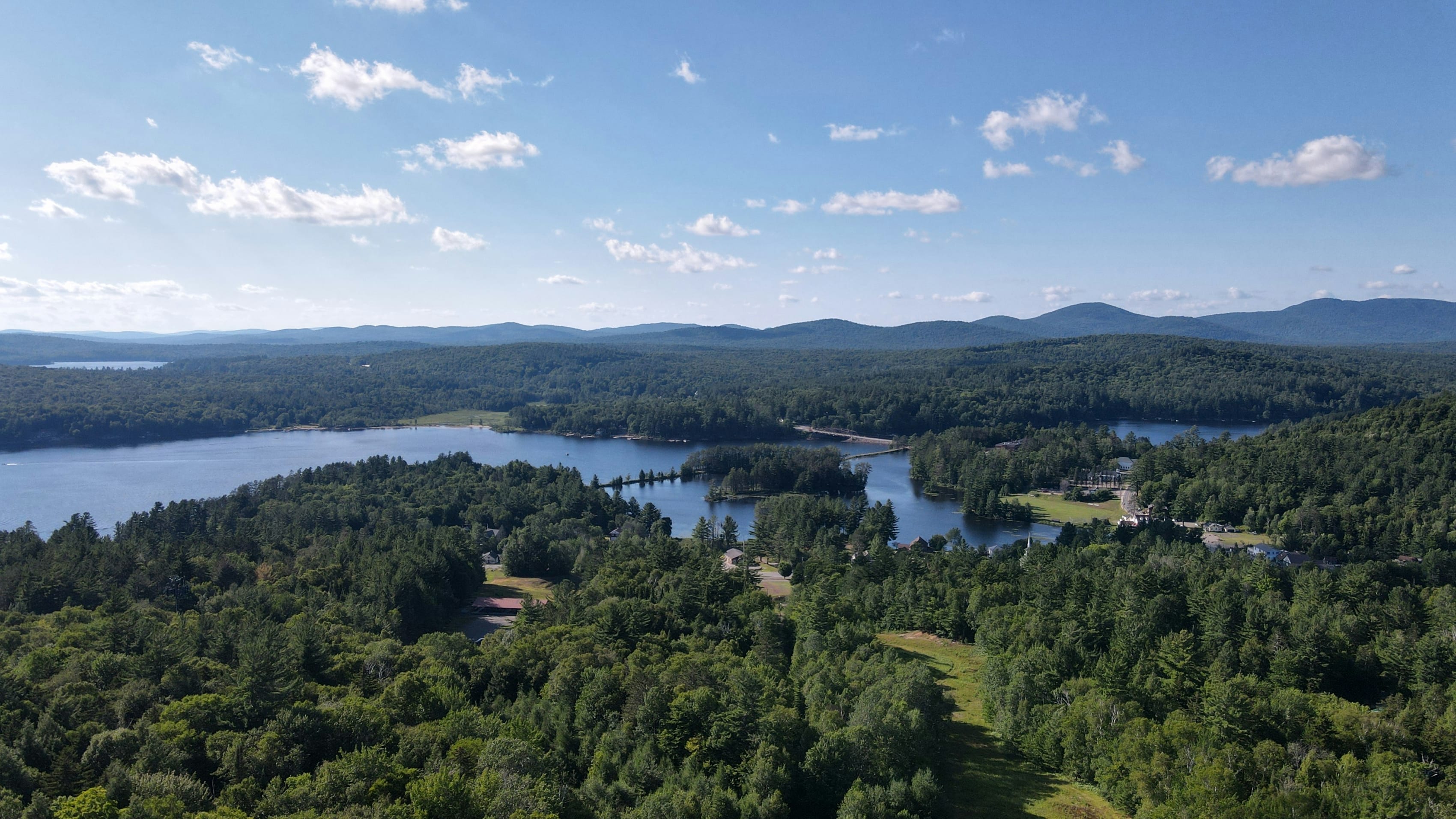 Aerial view showcasing the lush greenery and serene lakes of the New York wilderness, perfect for outdoor adventures.