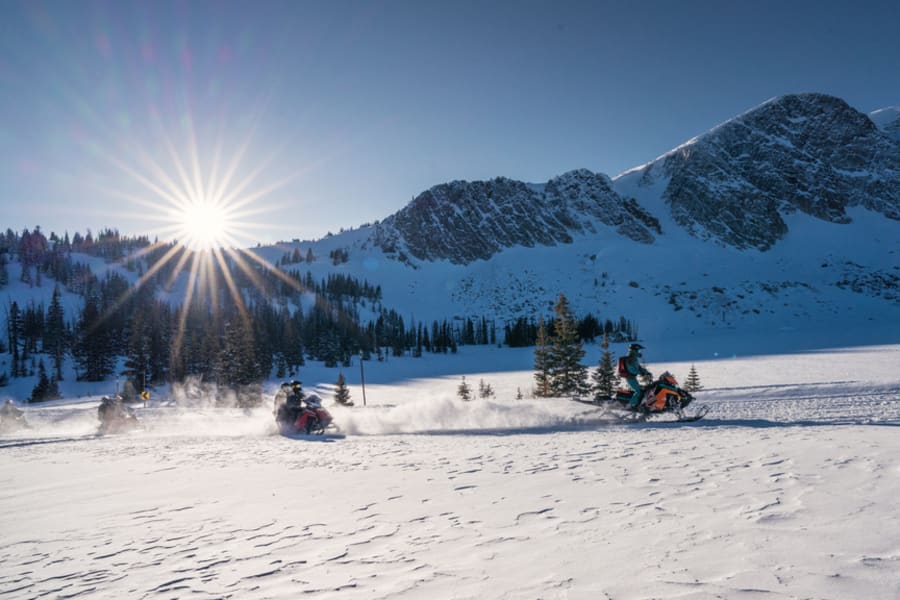 Two snowmobilers crossing open meadow