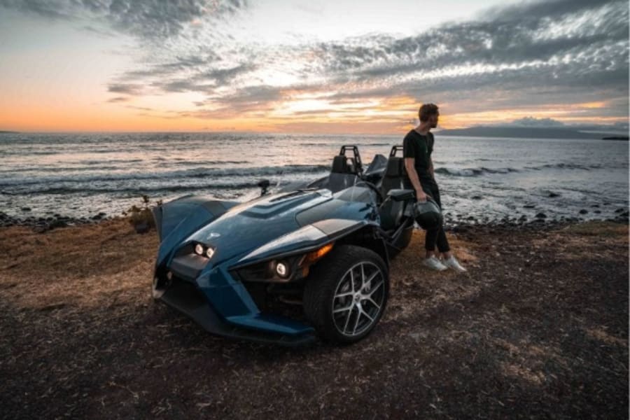 Man standing by Polaris Slingshot looking at sunset