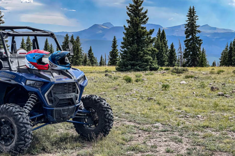 Polaris side by side with two helmets on hood.