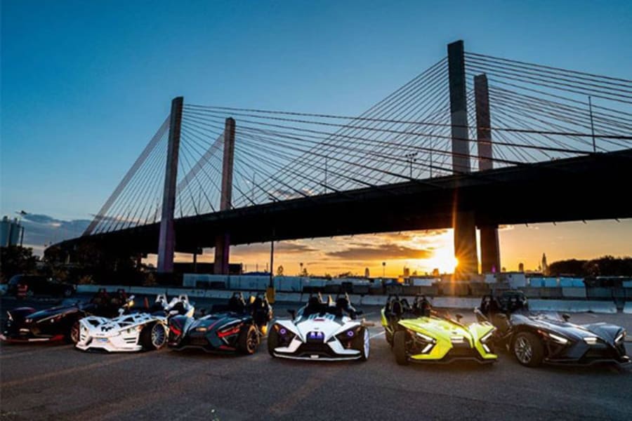 Polaris Slingshots parked by a large bridge