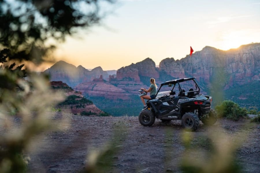 Woman sitting on hood of Polaris side by side in Sedona