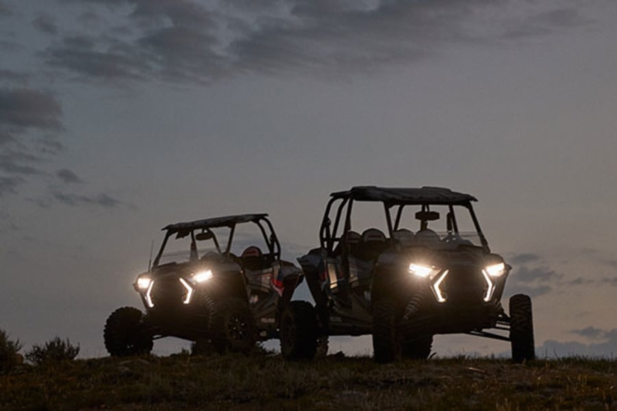Two Polaris ATVs with headlights on at night