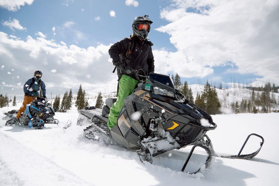 Snowmobiler standing astride snowmobile