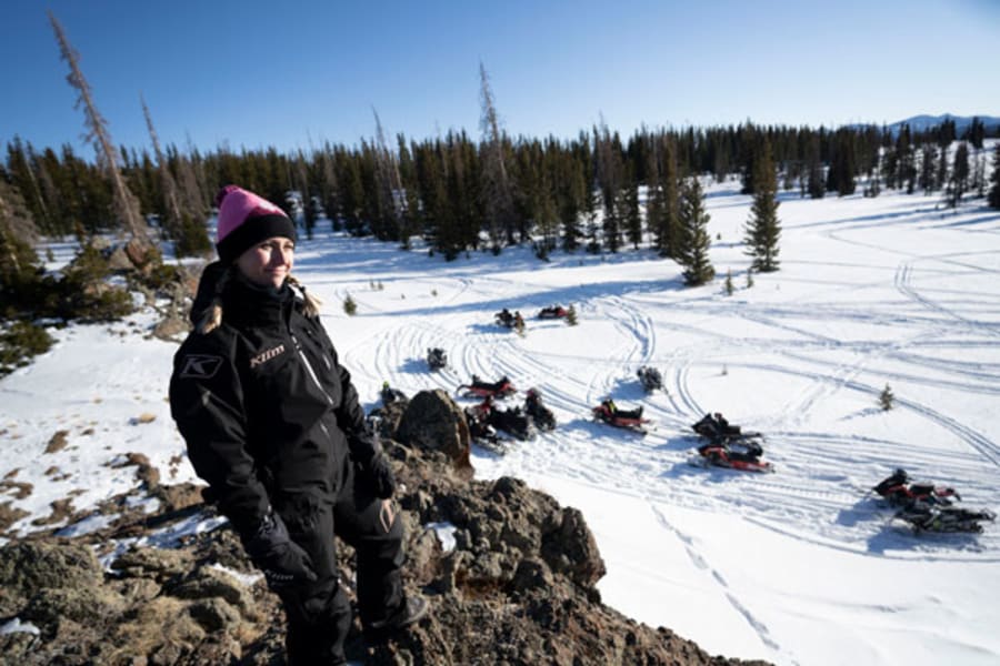 Woman standing on ridge above snowmobile gathering
