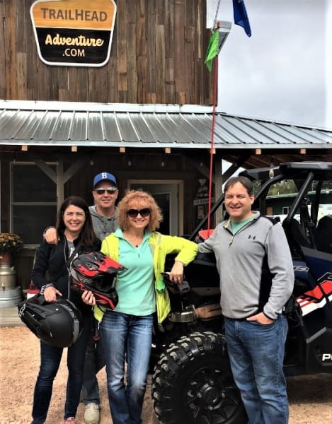 Two couples standing front of Polaris RZR