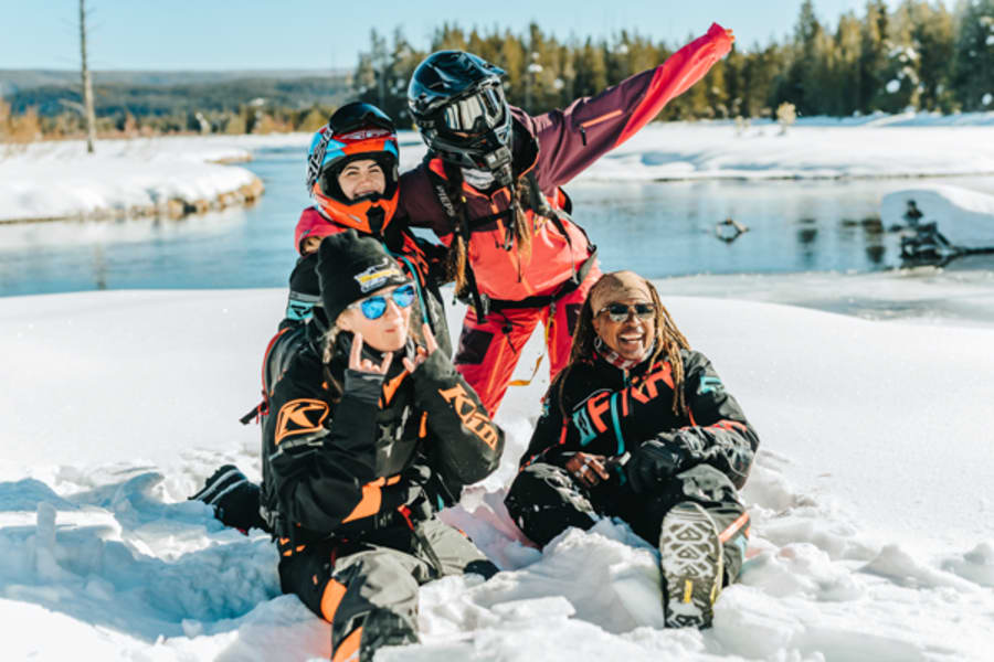 Four adults posing happily in snow