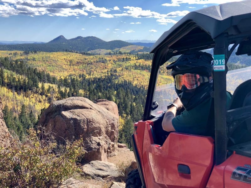 Polaris ATVs on a dirt trail through mountains
