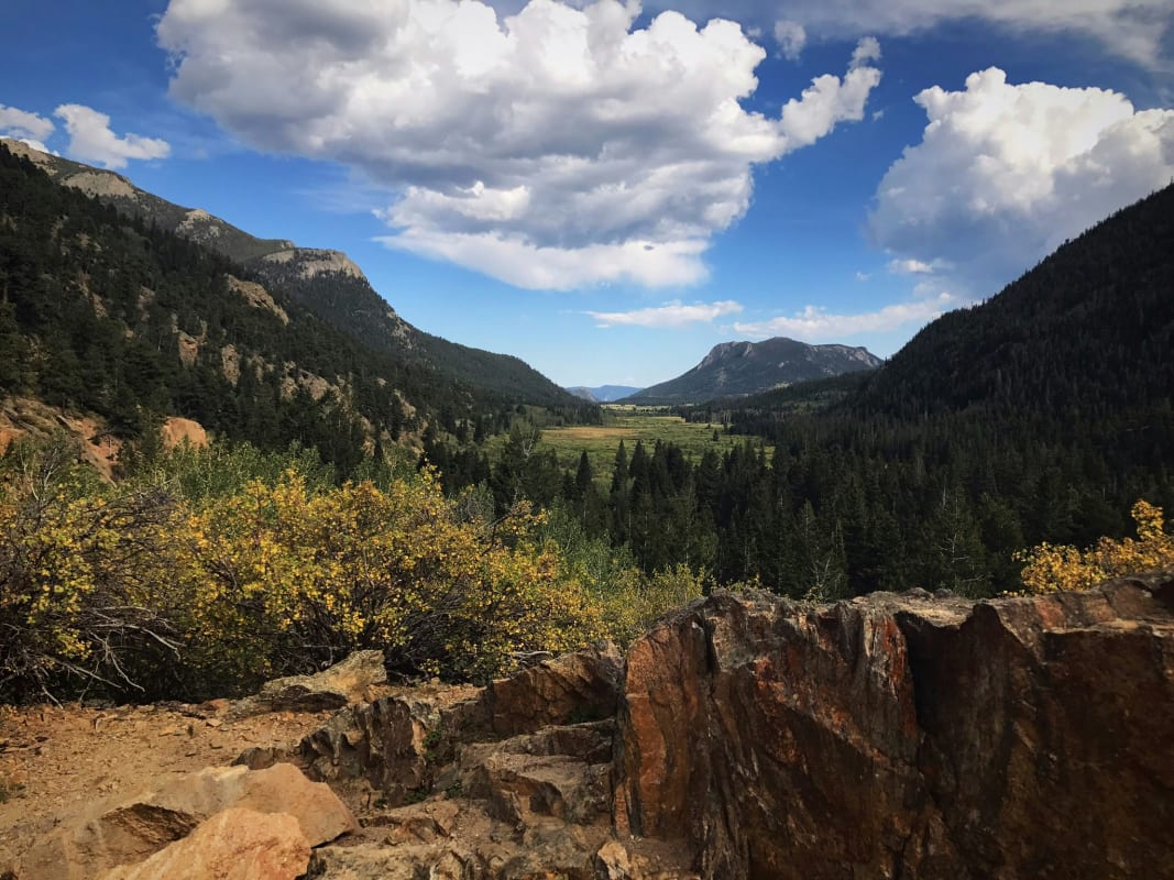 Scenic view of Rocky Mountain National Park with lush valleys and a vivid blue sky with fluffy clouds