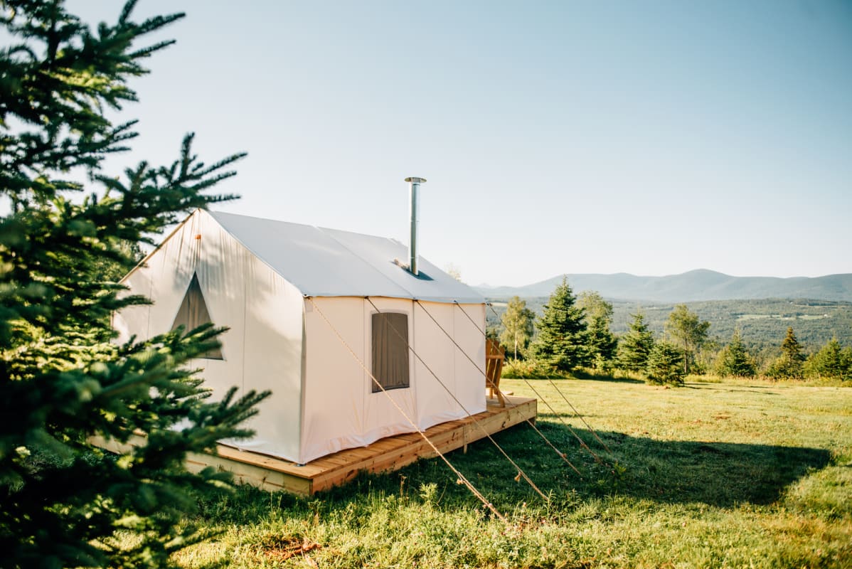 Canvas tent in a mountain meadow at sunset.