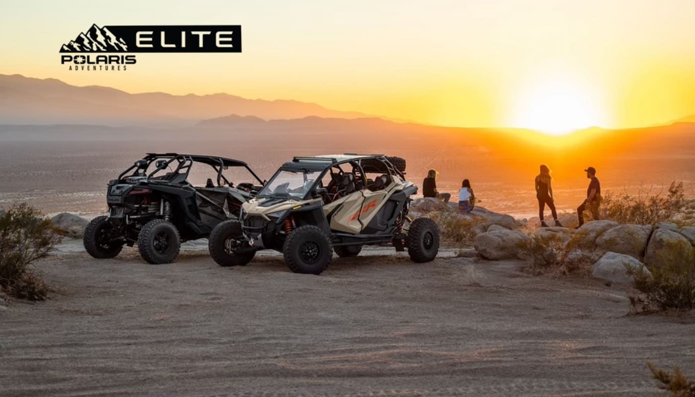 Polaris RZRs parked at desert overlook during sunset with Polaris Adventures Elite logo
