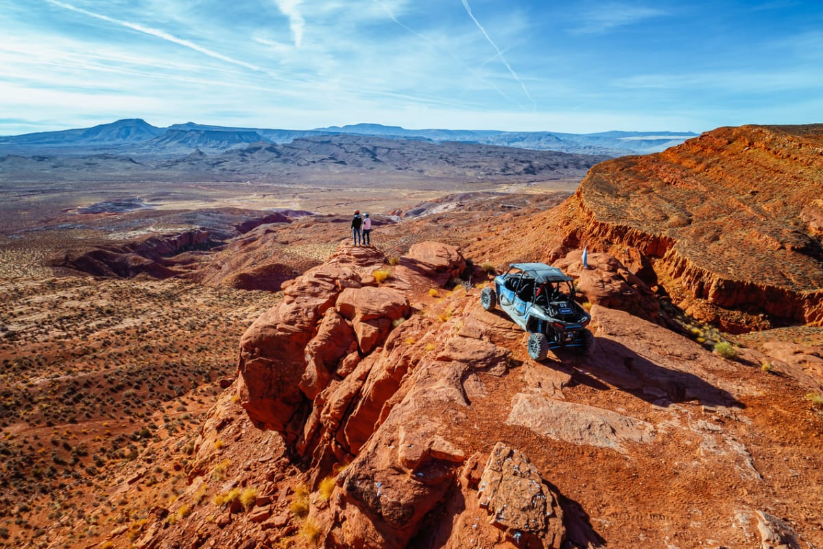 Polaris side-by-side parked on a red rock ridge overlooking a vast desert canyon.