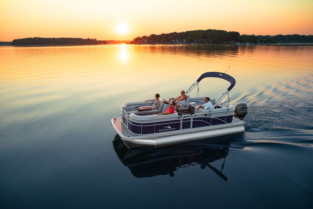 Group of friends enjoying a serene sunset cruise on a Bennington pontoon boat, reflecting a lifestyle of leisure and luxury on calm waters.