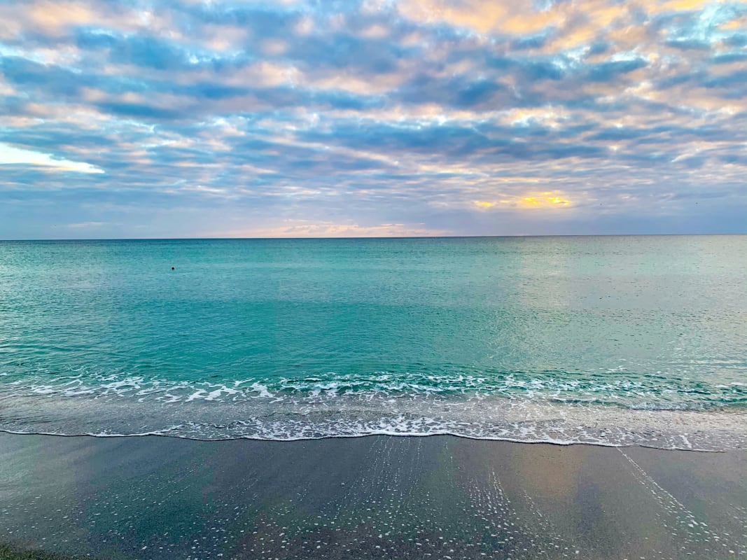 Serene Florida beach with gentle waves under a partly cloudy sky at sunrise or sunset
