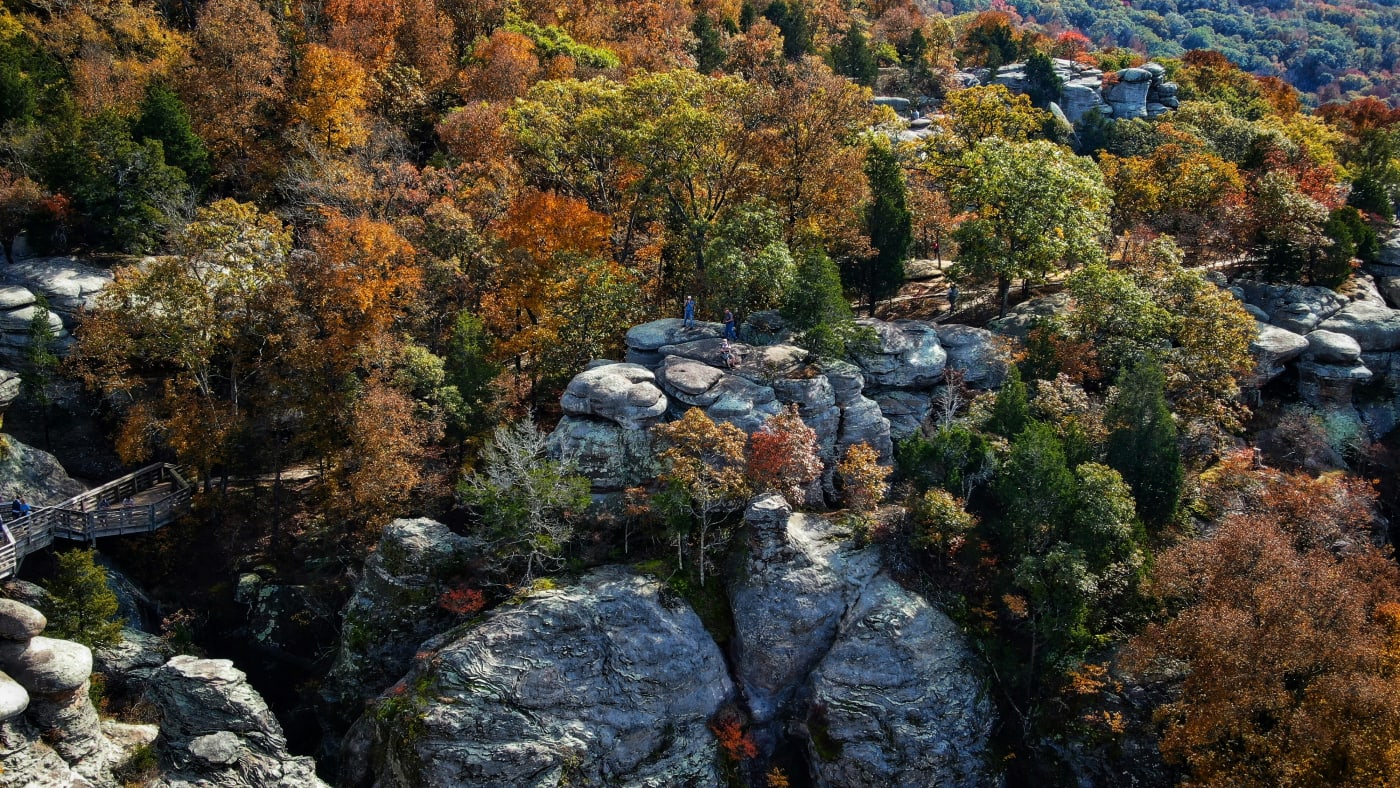Aerial view of Illinois rocky landscape with colorful autumn foliage and a walking trail visible among the trees.