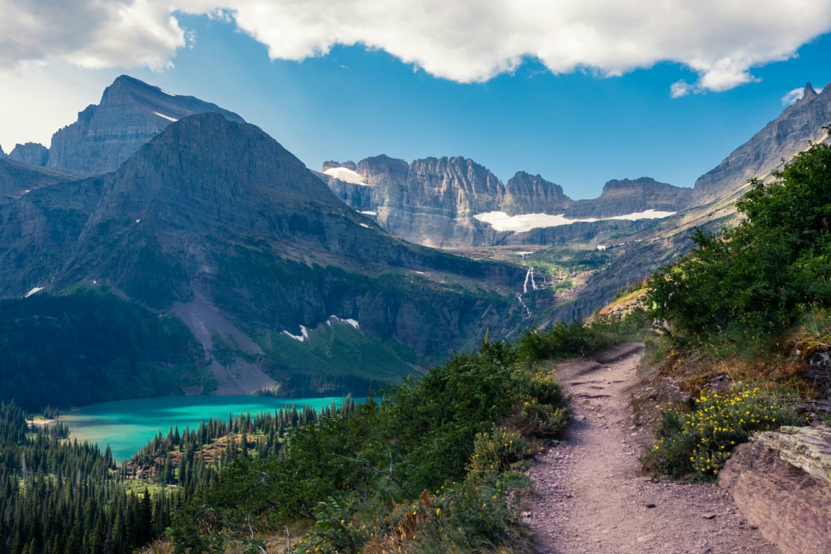 Scenic view of a trail in Montana with towering mountains and a turquoise lake in the distance