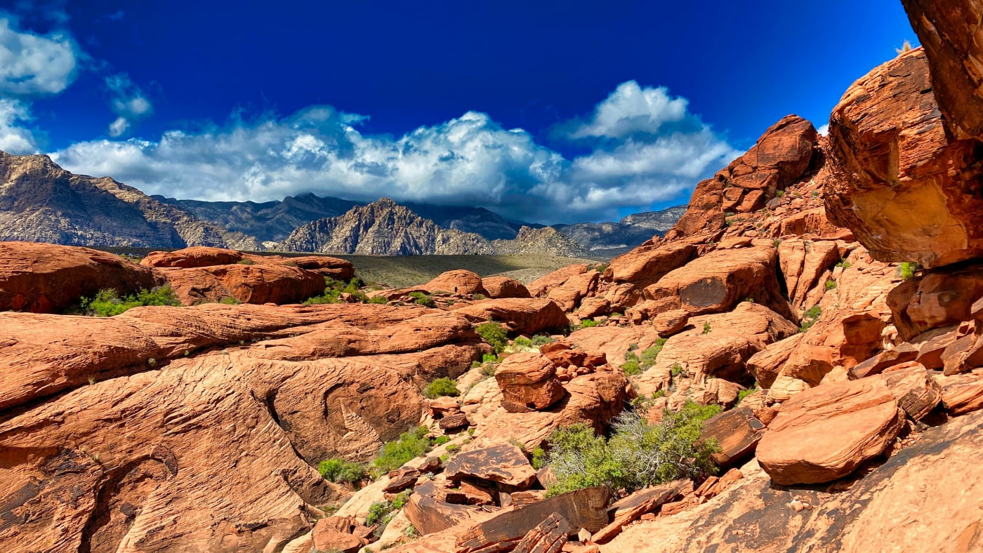 Vibrant red rock formations under a blue sky with fluffy clouds in Nevada's desert landscape