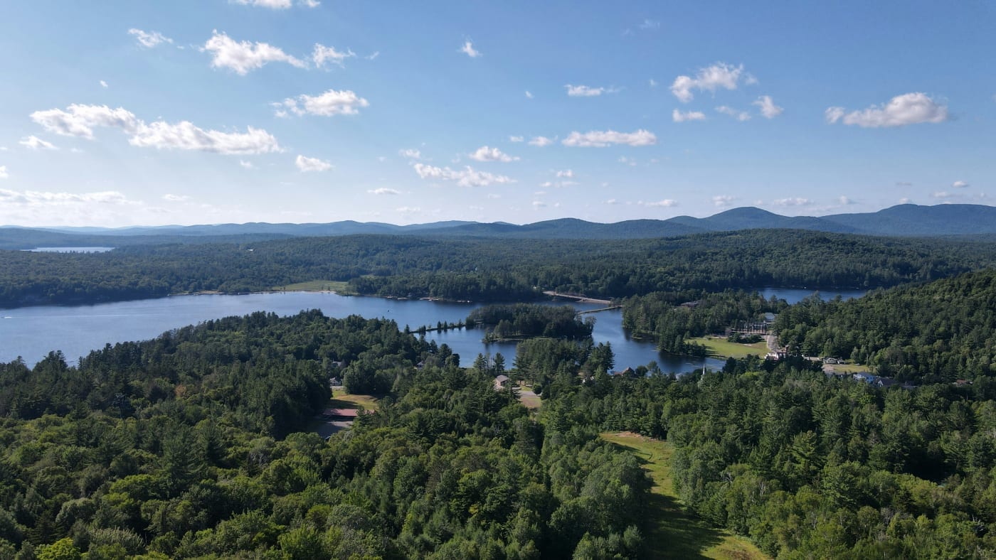 Aerial view showcasing the lush greenery and serene lakes of the New York wilderness, perfect for outdoor adventures.