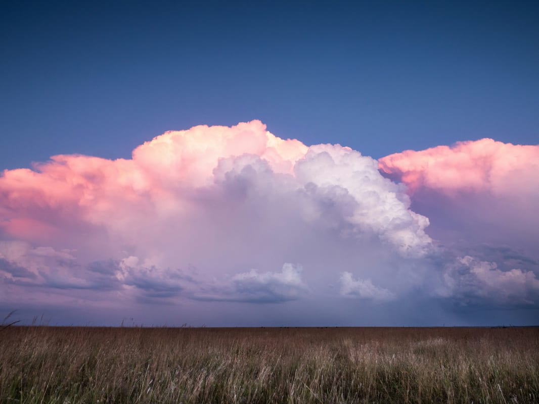 Expansive Oklahoma grassland under a majestic cloudscape at dusk, highlighting the state’s natural beauty.