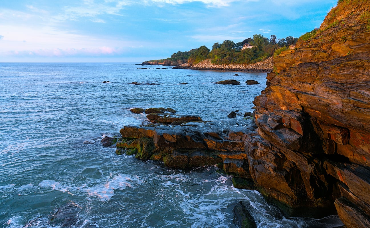 Scenic view of the rocky coastline in Rhode Island during sunset with vibrant sky colors