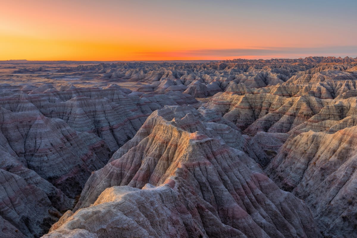 Sunset view over the rugged landscapes of South Dakota's Badlands with warm hues on the horizon