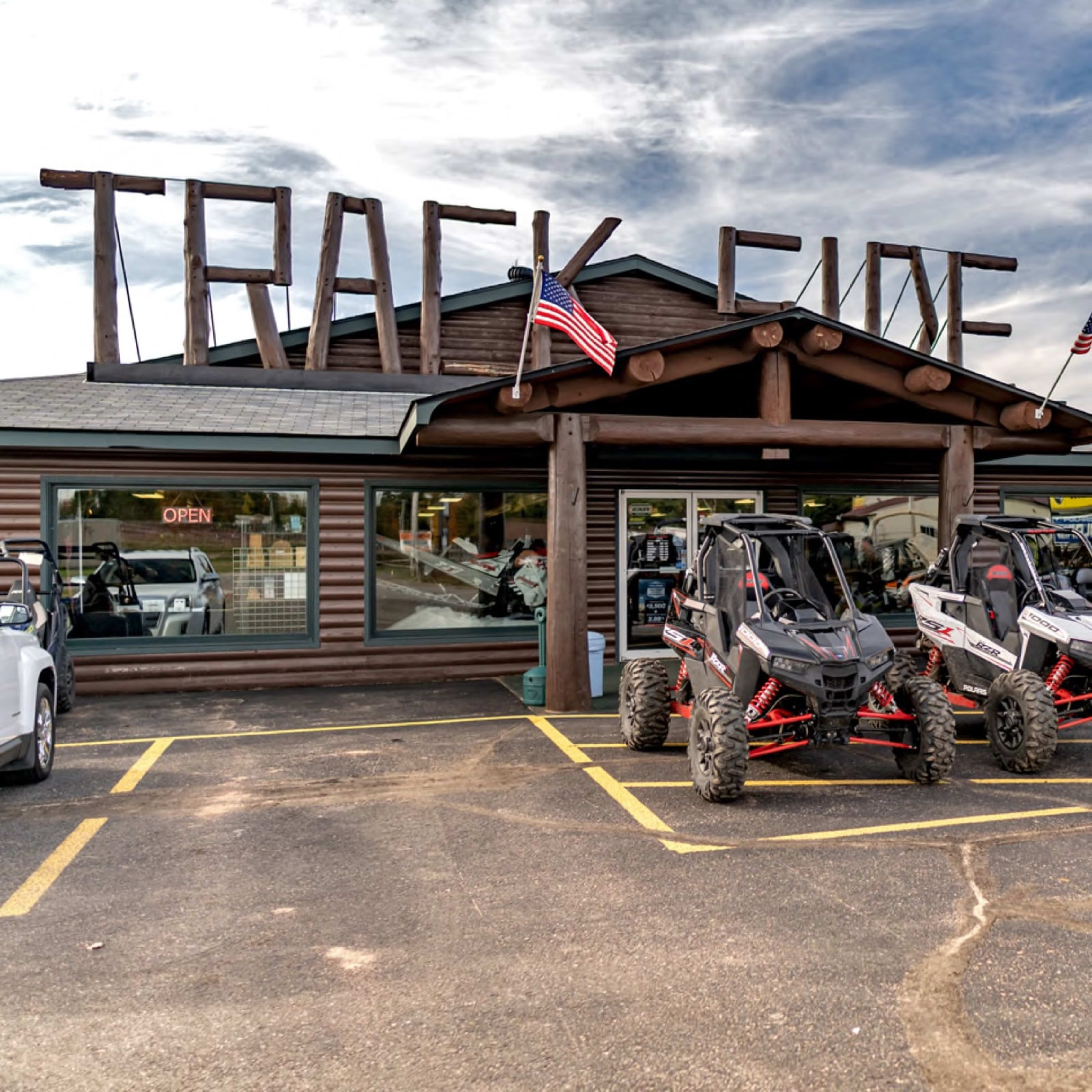 Exterior of 'TRACK FIVE' store with parked off-road vehicles and American flags.