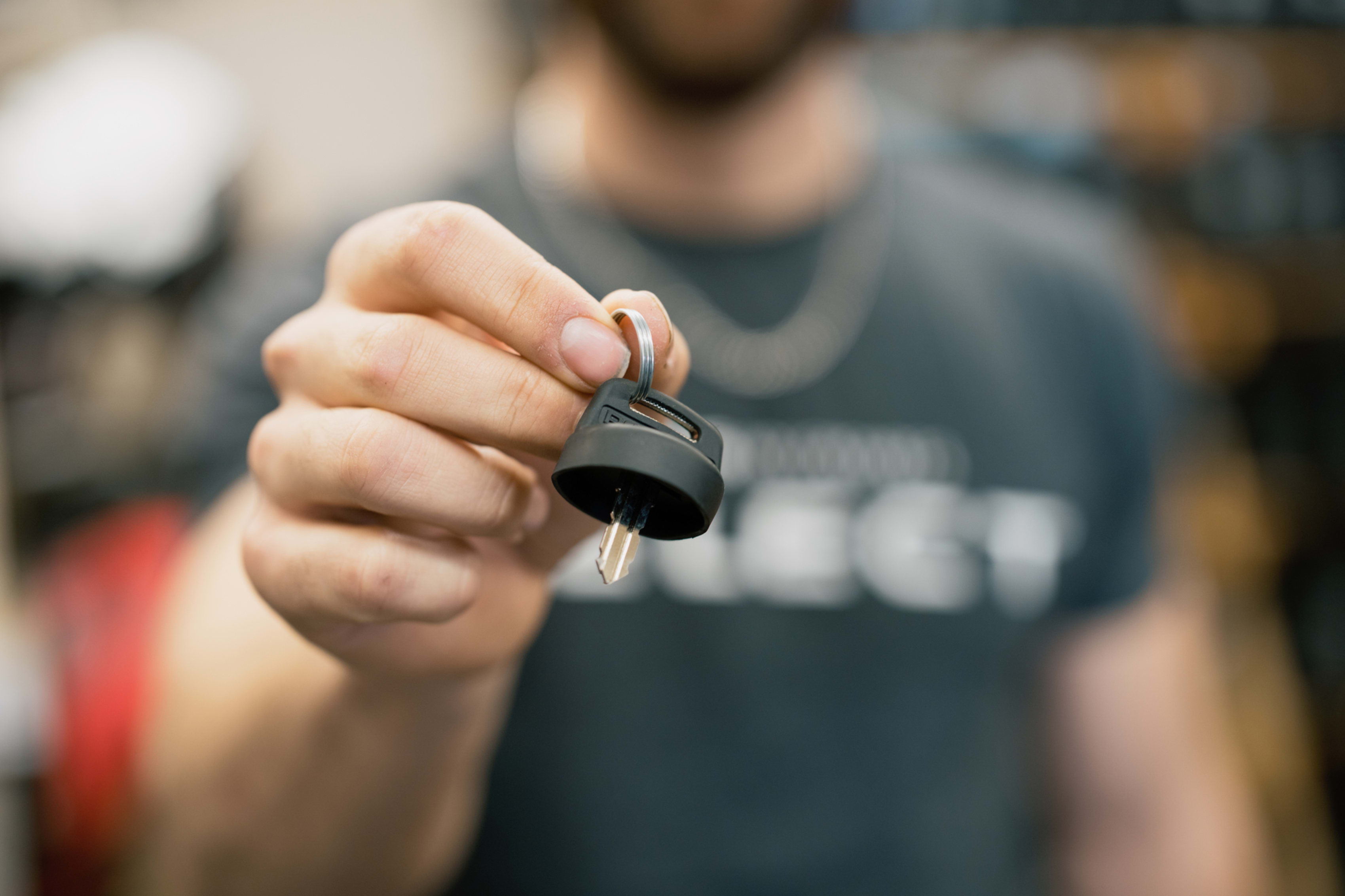 A person holds out a key attached to a black plastic fob.