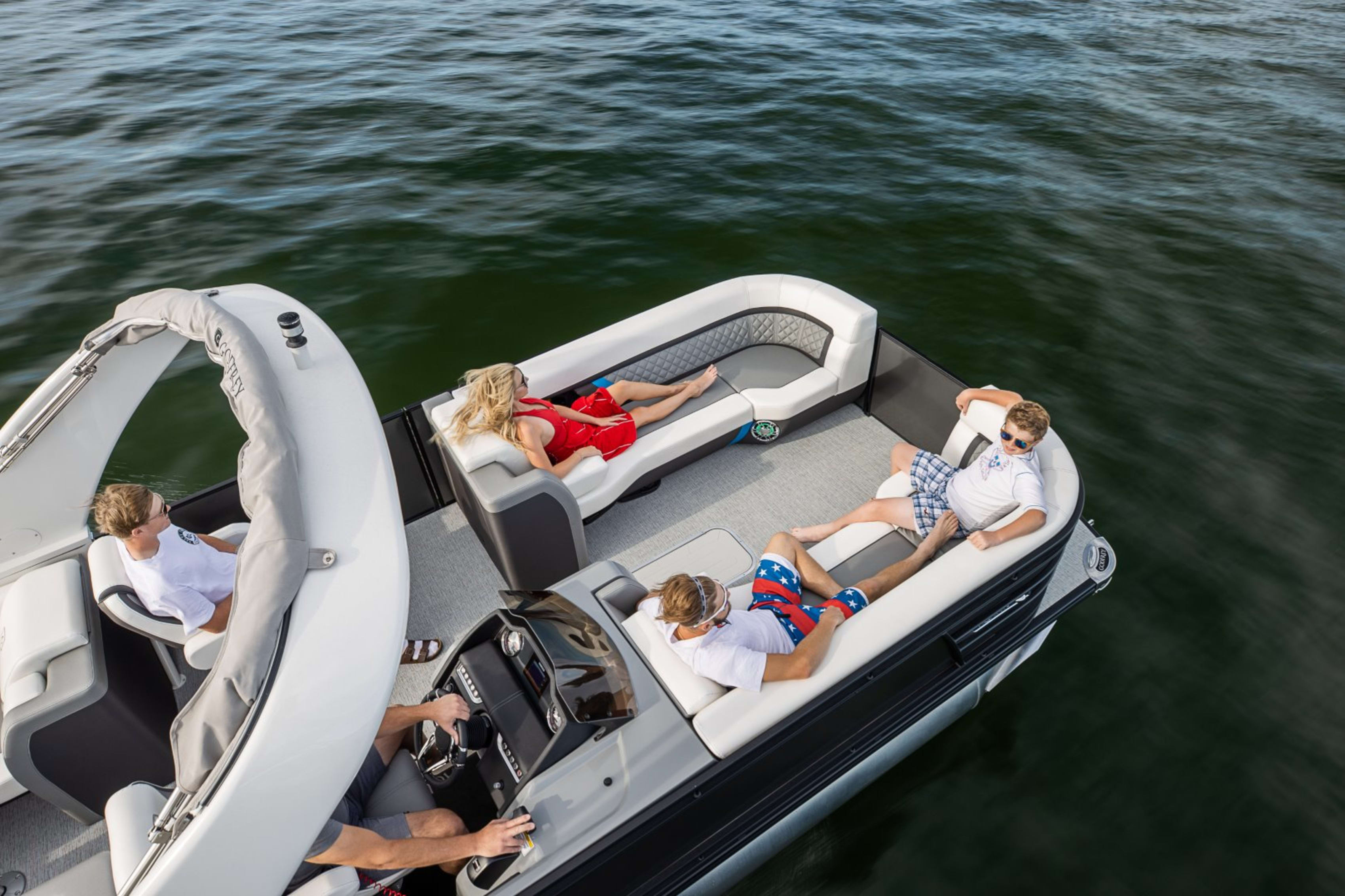 Family and friends enjoying a leisurely day on a modern pontoon boat, relaxing on the comfortable seats under the bright sun, surrounded by calm waters.